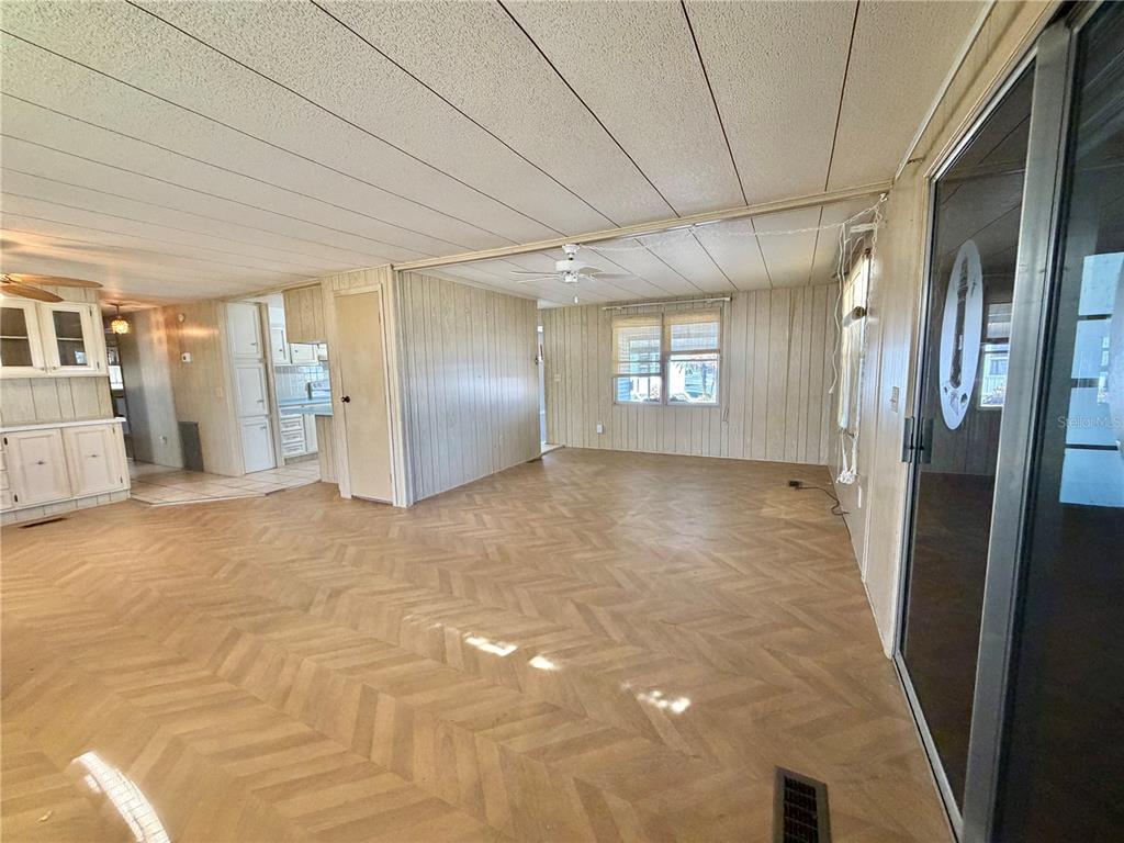 An interior view of a living room with wood-look flooring, wood paneling, and a ceiling fan — 353 PALO VERDE DRIVE, LEESBURG, FL