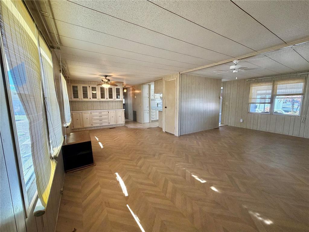 A living room with wood-paneled walls, herringbone flooring, built-in cabinetry, and a ceiling fan — 353 PALO VERDE DRIVE, LEESBURG, FL