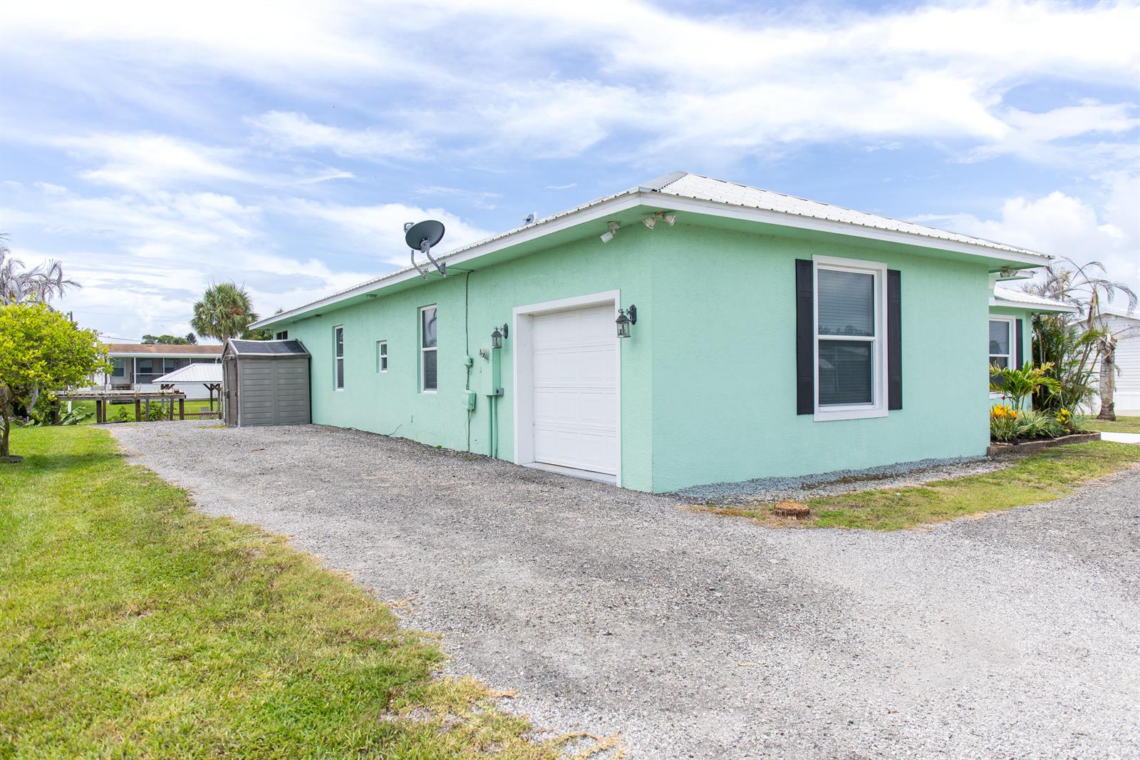 A light green house with a white garage door and a gravel driveway — 2406 SE 31st Street SE, Okeechobee FL 34974, OKEECHOBEE, FL