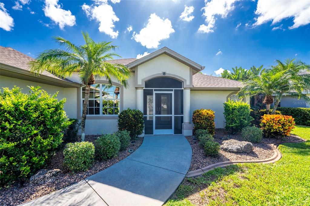 A concrete walkway leads to the screened front entryway of a single-story suburban home — 8 SPORTSMAN ROAD, ROTONDA WEST, FL