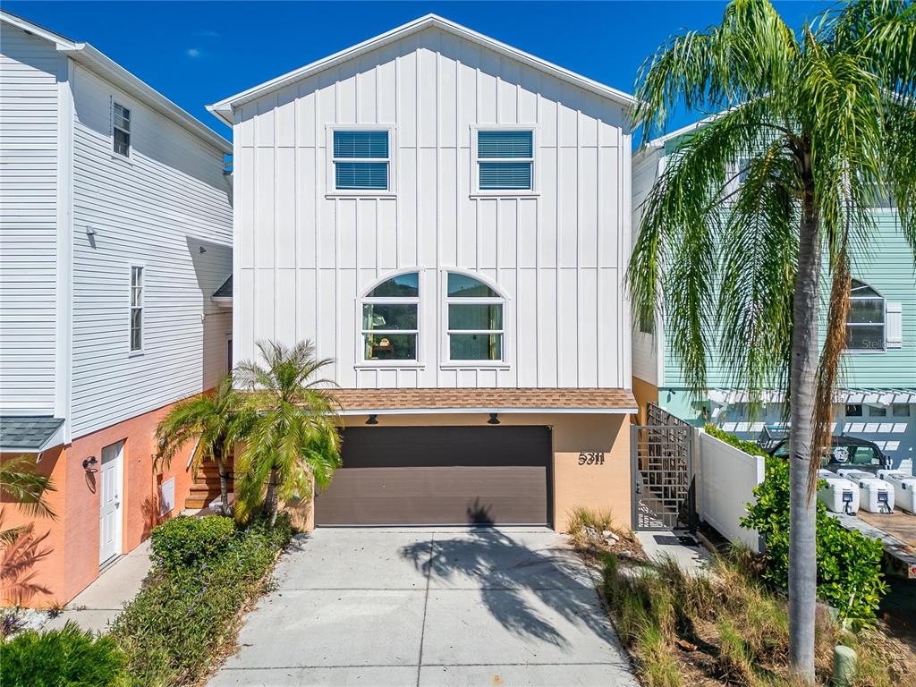 A two-story house with white vertical siding, a brown garage door, and arched windows — 5311 BOARDWALK STREET, HOLIDAY, FL