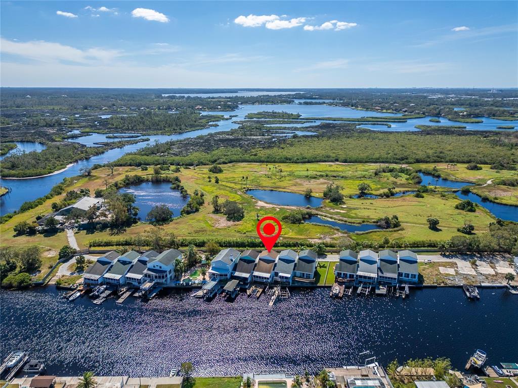 An aerial view shows a row of waterfront townhomes along a canal near wetlands — 5311 BOARDWALK STREET, HOLIDAY, FL
