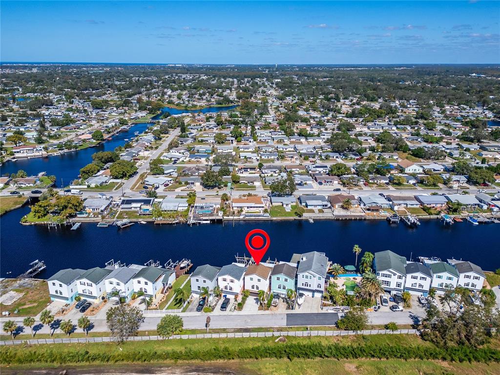 An aerial view shows a row of waterfront houses along a canal with a red marker — 5311 BOARDWALK STREET, HOLIDAY, FL