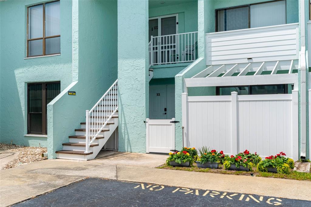 A teal two-story building exterior features a white staircase, a gated entrance, and parking restrictions — 1 WINDRUSH BOULEVARD UNIT 101, INDIAN ROCKS BEACH, FL