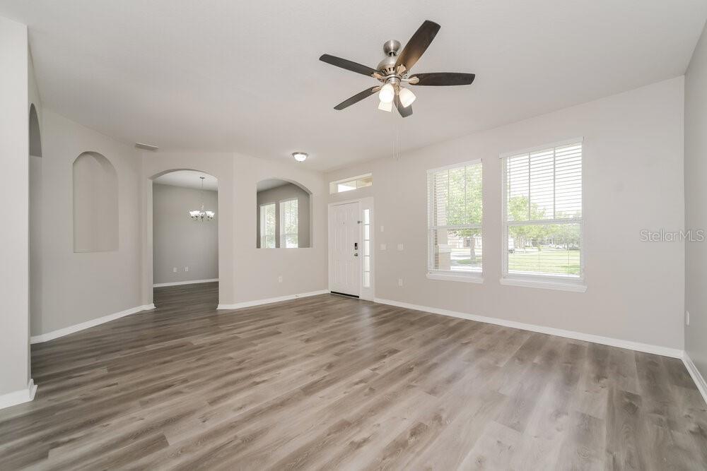 A living room with light gray wood-look flooring, white walls, and a ceiling fan — 3391 MARSHFIELD PRESERVE WAY, KISSIMMEE, FL