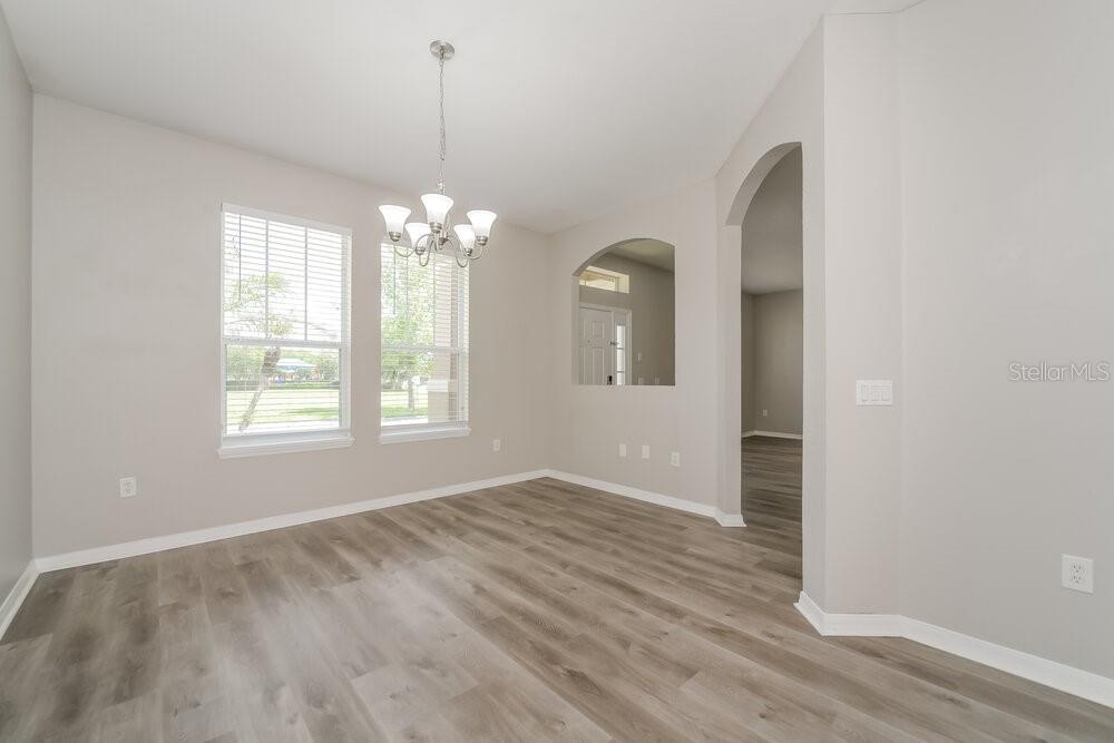 A dining room with light gray walls, wood-look flooring, and a modern chandelier — 3391 MARSHFIELD PRESERVE WAY, KISSIMMEE, FL
