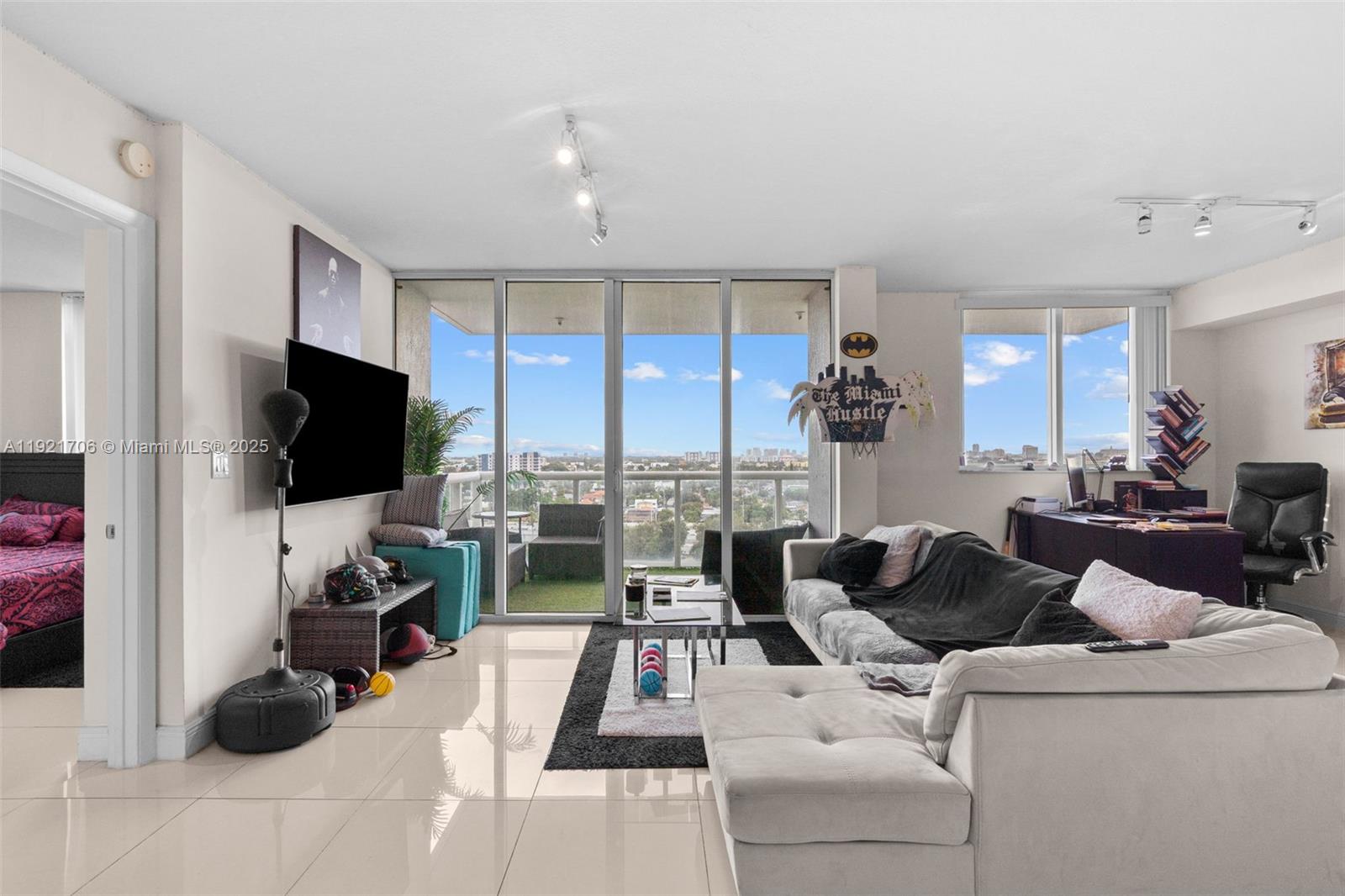 A living room features a white sectional sofa, a television, and a balcony with views — 1871 NW S River Dr # 1402, Miami FL 33125, MIAMI, FL
