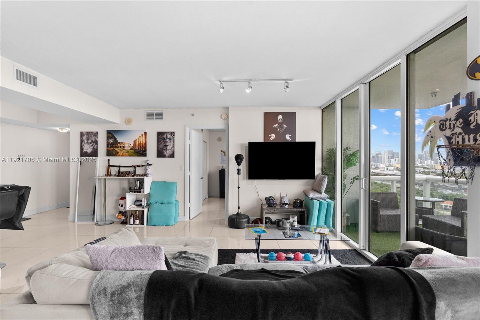 A living room features a white sectional sofa, a wall-mounted television, and a balcony view — 1871 NW S River Dr # 1402, Miami FL 33125, MIAMI, FL