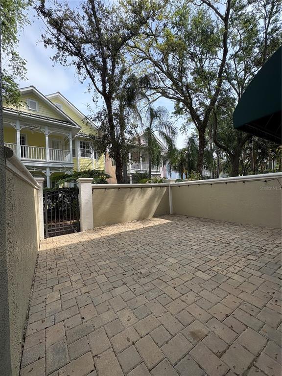 A paved patio is enclosed by a low stucco wall with a metal gate — 1407 HARBOUR WALK ROAD, TAMPA, FL