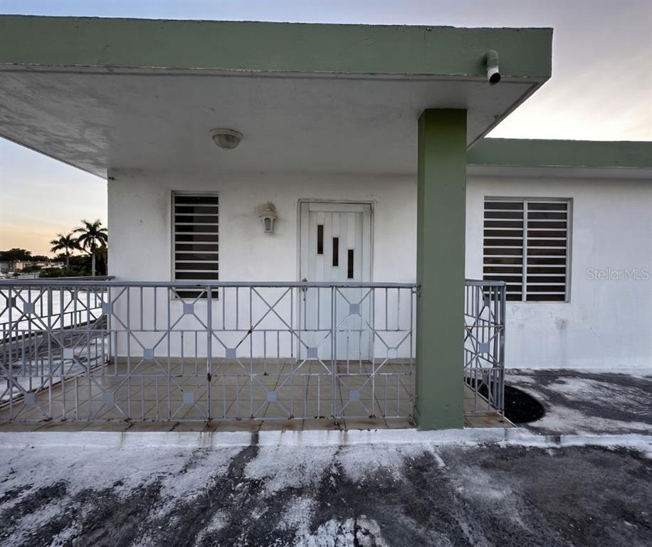 A white exterior wall features a covered porch with a metal railing and a door — 89 BLOCK 92 VILLA CAROLINA DEV. UNIT 11, CAROLINA, PR
