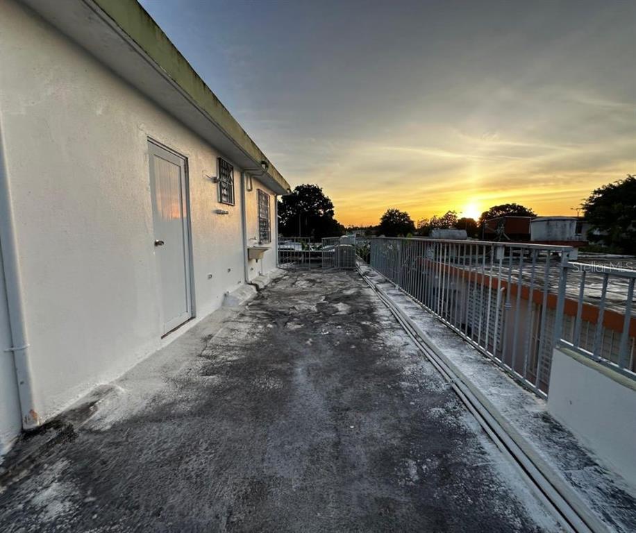 An outdoor rooftop terrace with a white wall, metal railing, and a sunset view — 89 BLOCK 92 VILLA CAROLINA DEV. UNIT 11, CAROLINA, PR
