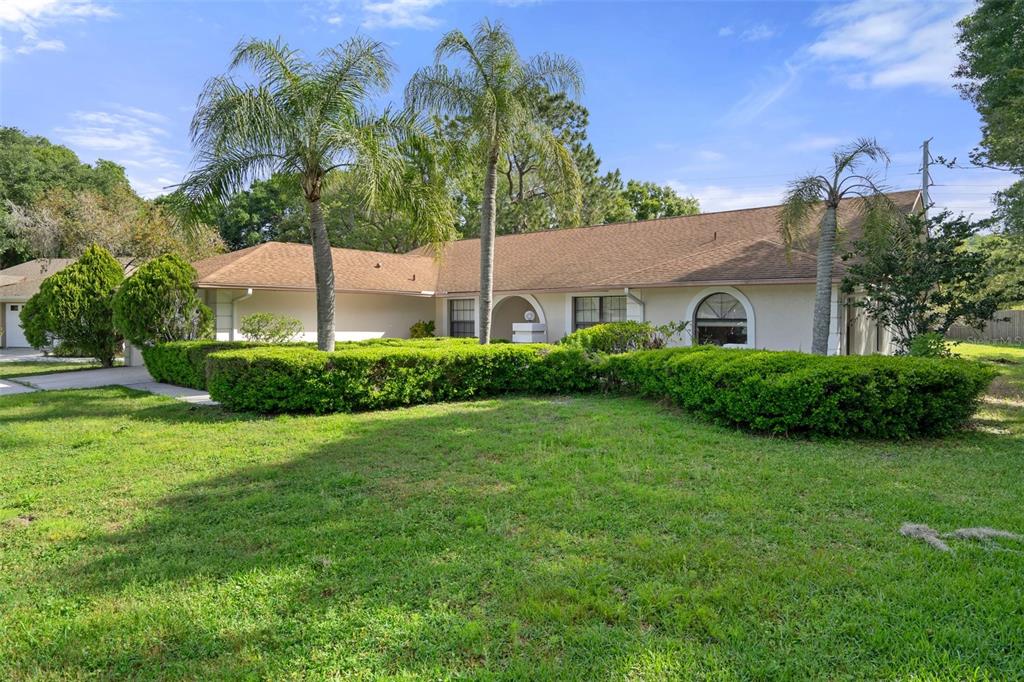 A spacious living room with light wood-look flooring, vaulted ceilings, and a kitchen pass-through — 16125 ANCROFT COURT, TAMPA, FL