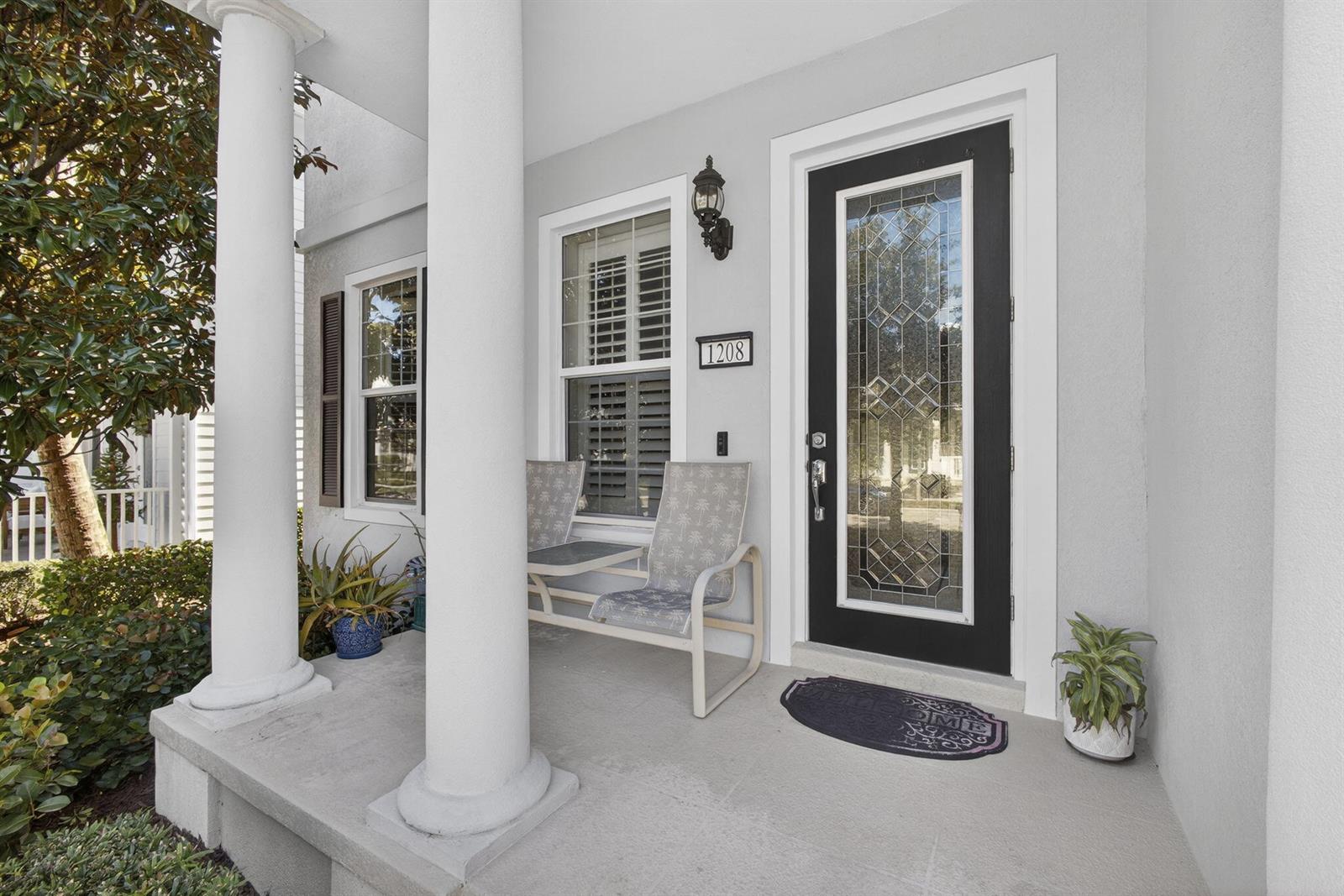 A covered front porch features white columns, a black front door, and two patio chairs — 1208 Islamorada Drive, Jupiter FL 33458, JUPITER, FL