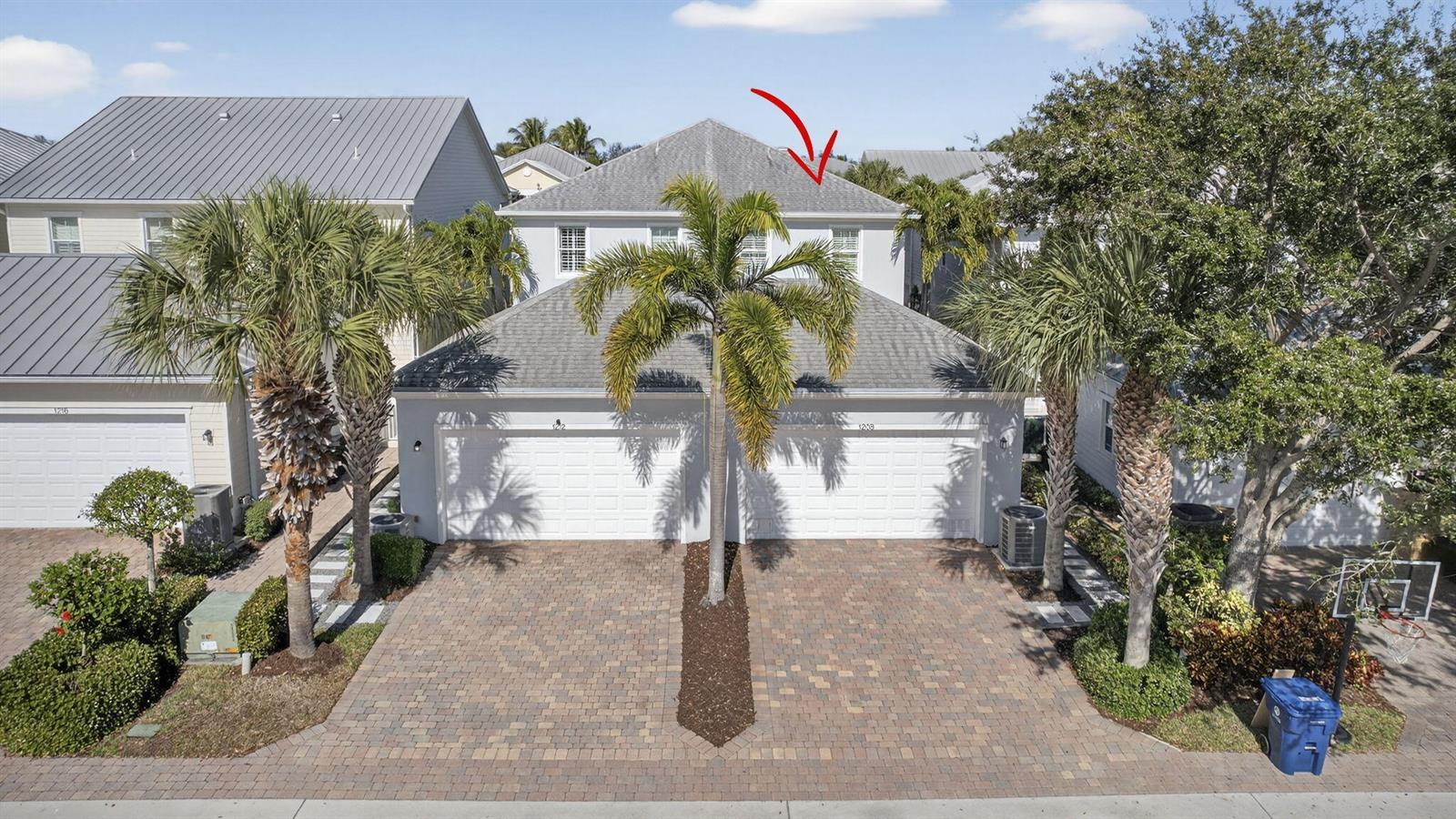 An exterior view of a two-story duplex with a paved driveway and palm trees — 1208 Islamorada Drive, Jupiter FL 33458, JUPITER, FL
