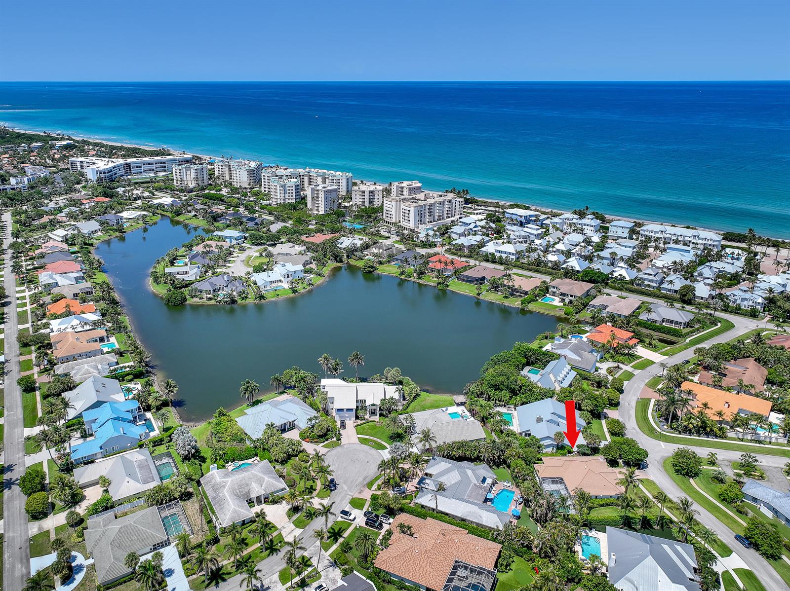 An aerial view shows a residential neighborhood with a lake and the ocean nearby — 121 Olympus Way, Jupiter FL 33477, JUPITER, FL