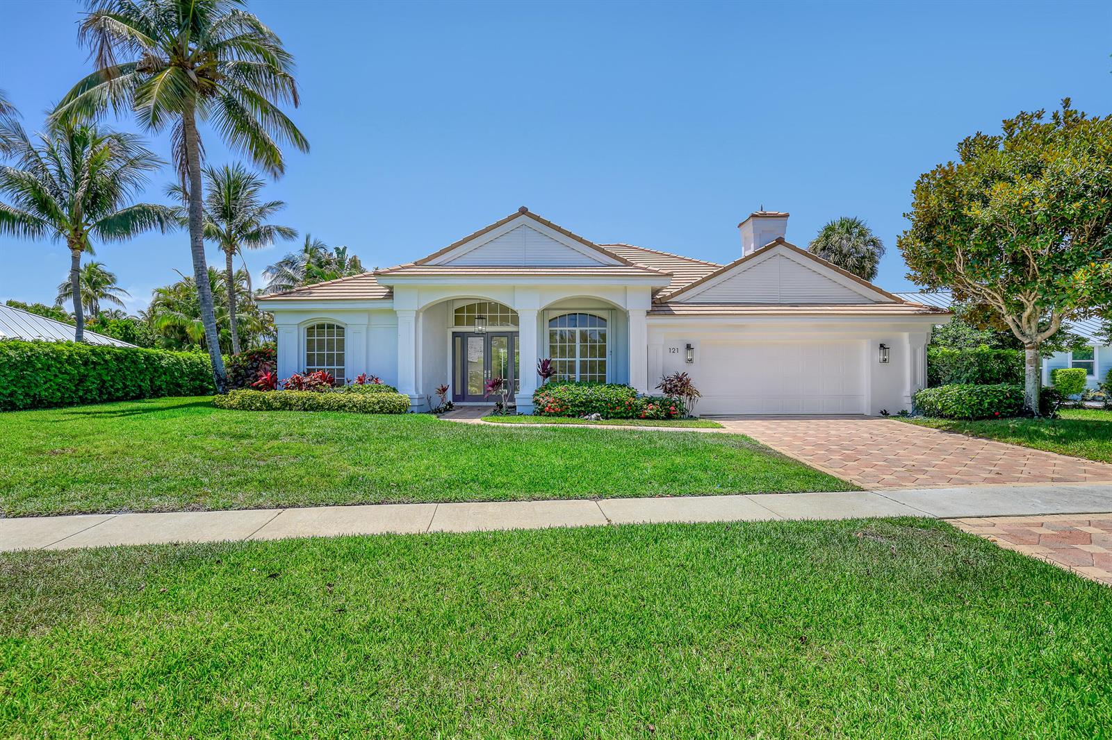 A single-story white house with a tile roof, arched entryway, and a paved driveway — 121 Olympus Way, Jupiter FL 33477, JUPITER, FL