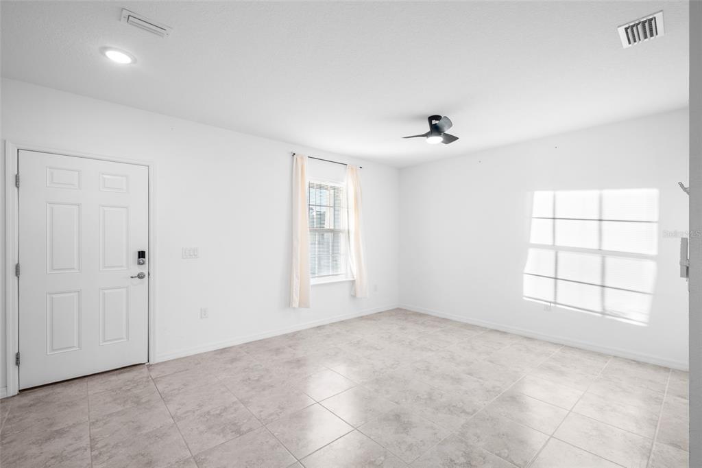 An empty room with white walls, light tile flooring, a ceiling fan, and two windows — 2151 NW 248TH WAY, NEWBERRY, FL