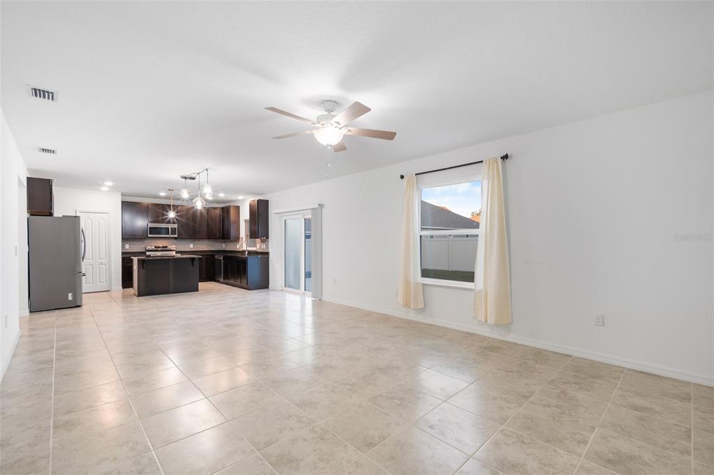 A kitchen features dark wood cabinets, stainless steel appliances, a granite island, and tile flooring — 2151 NW 248TH WAY, NEWBERRY, FL