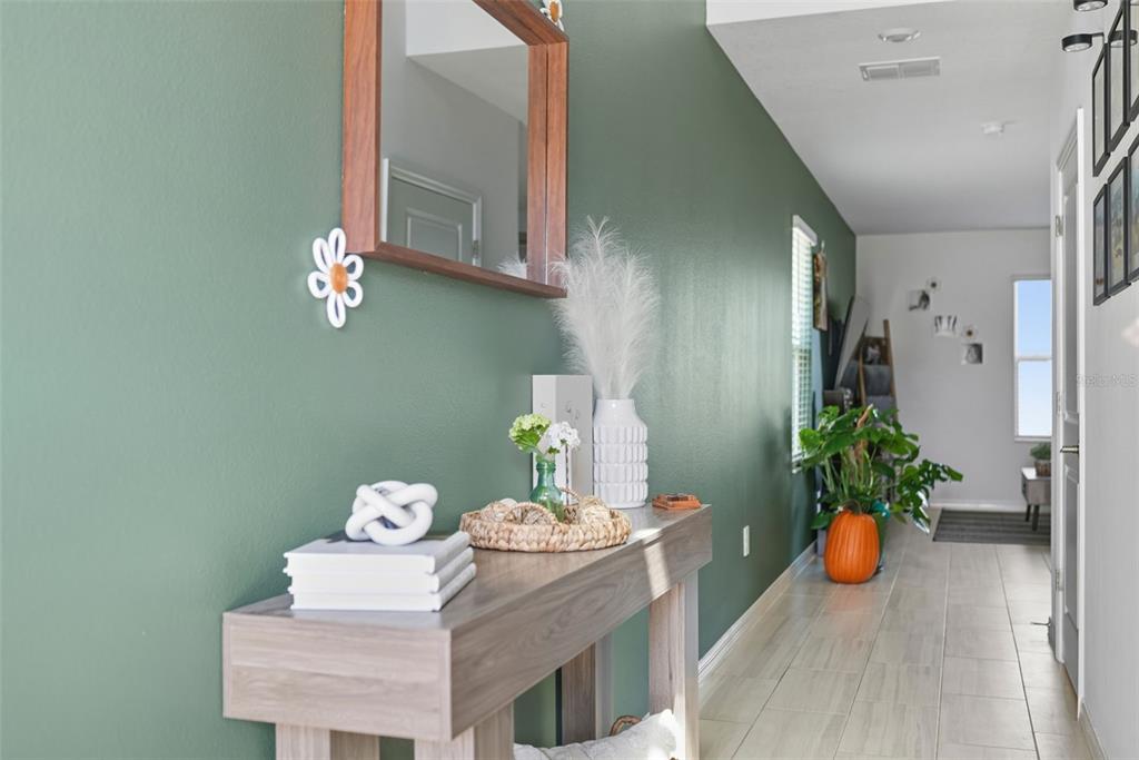 A hallway features a green accent wall, a wooden console table, and a mirror — 22289 NEBULA WAY, LAND O LAKES, FL