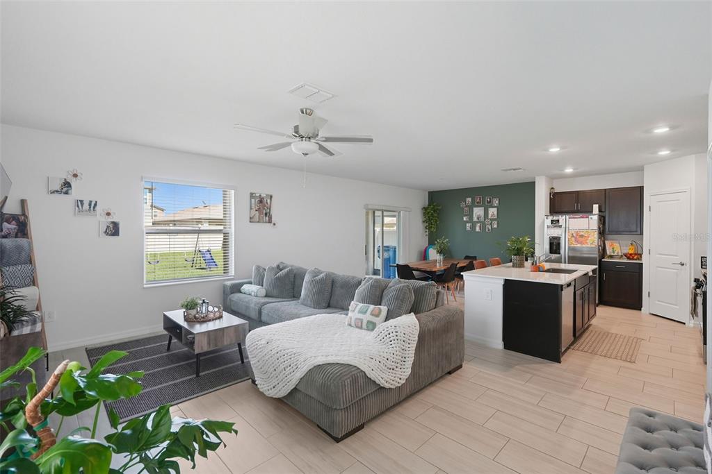 An open-concept living room and kitchen featuring a grey sectional sofa and dark cabinetry — 22289 NEBULA WAY, LAND O LAKES, FL