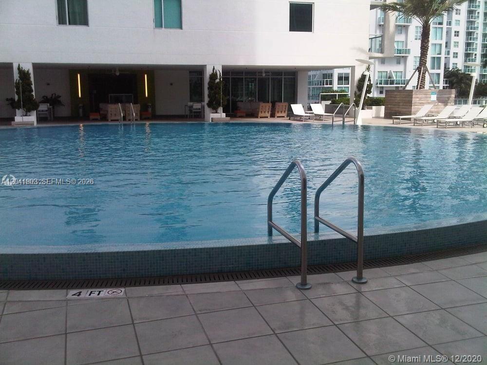 A swimming pool with a metal ladder and lounge chairs on a tiled deck — 500 Brickell Ave # 2604, Miami FL 33131, MIAMI, FL