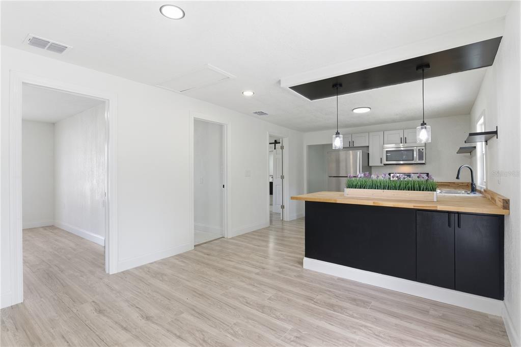 A kitchen with a black island and wooden countertop opens into a bright living area — 1104 E 8 TH STREET, SANFORD, FL