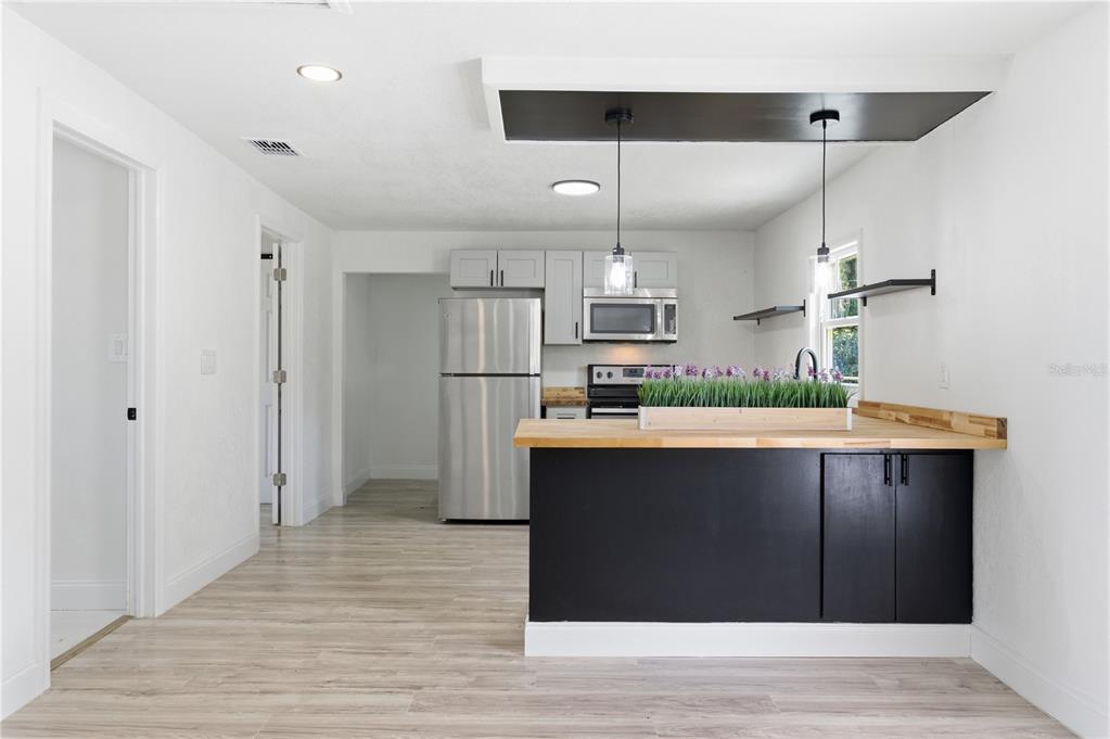 A kitchen features a black island with a wood countertop, stainless appliances, and white cabinetry — 1104 E 8 TH STREET, SANFORD, FL