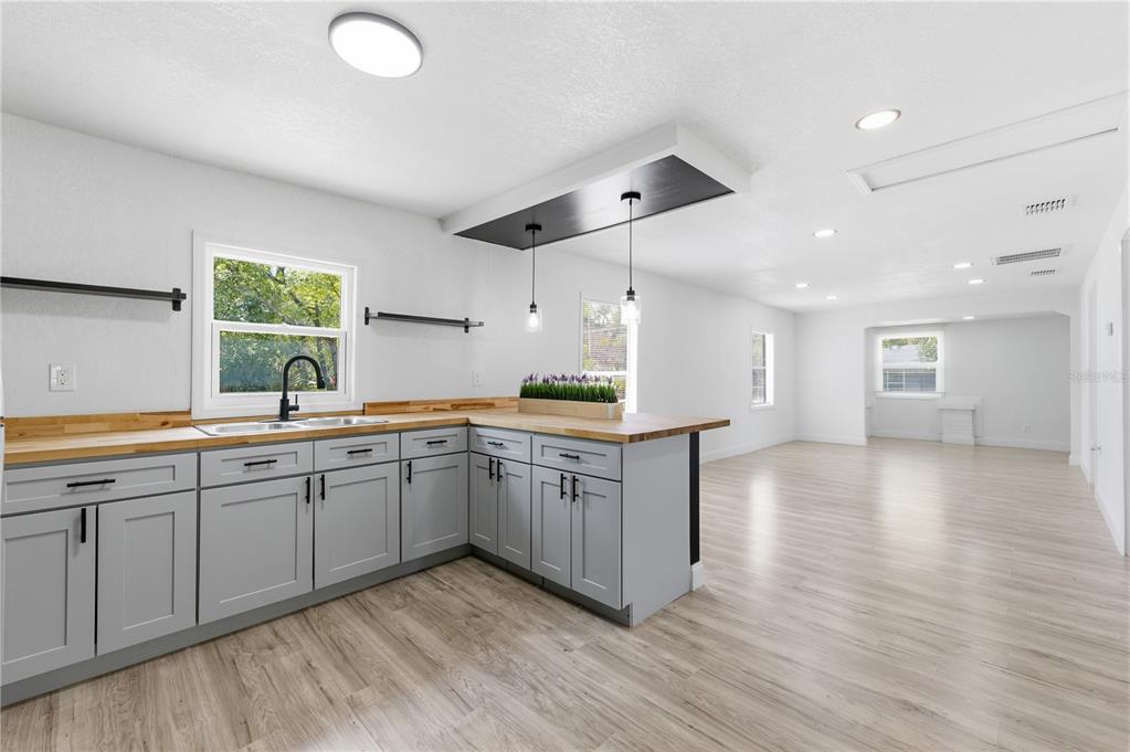 A kitchen with gray cabinets, wooden countertops, and a breakfast bar opens to a living area — 1104 E 8 TH STREET, SANFORD, FL