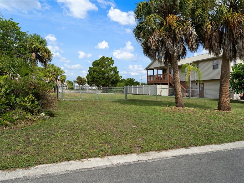 A grassy vacant lot is enclosed by a chain-link fence next to a two-story house — 3287 SEA GRAPE DRIVE, HERNANDO BEACH, FL