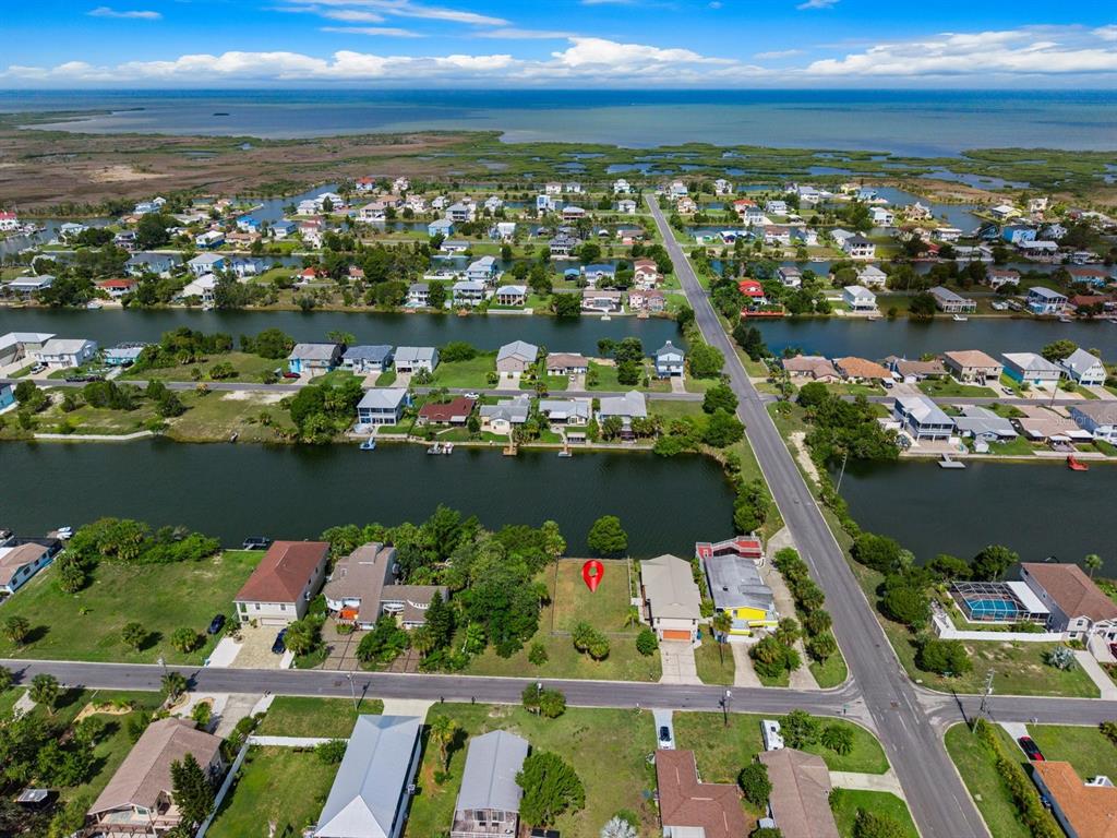 An aerial view shows a vacant waterfront lot marked with a red pin in a neighborhood — 3287 SEA GRAPE DRIVE, HERNANDO BEACH, FL