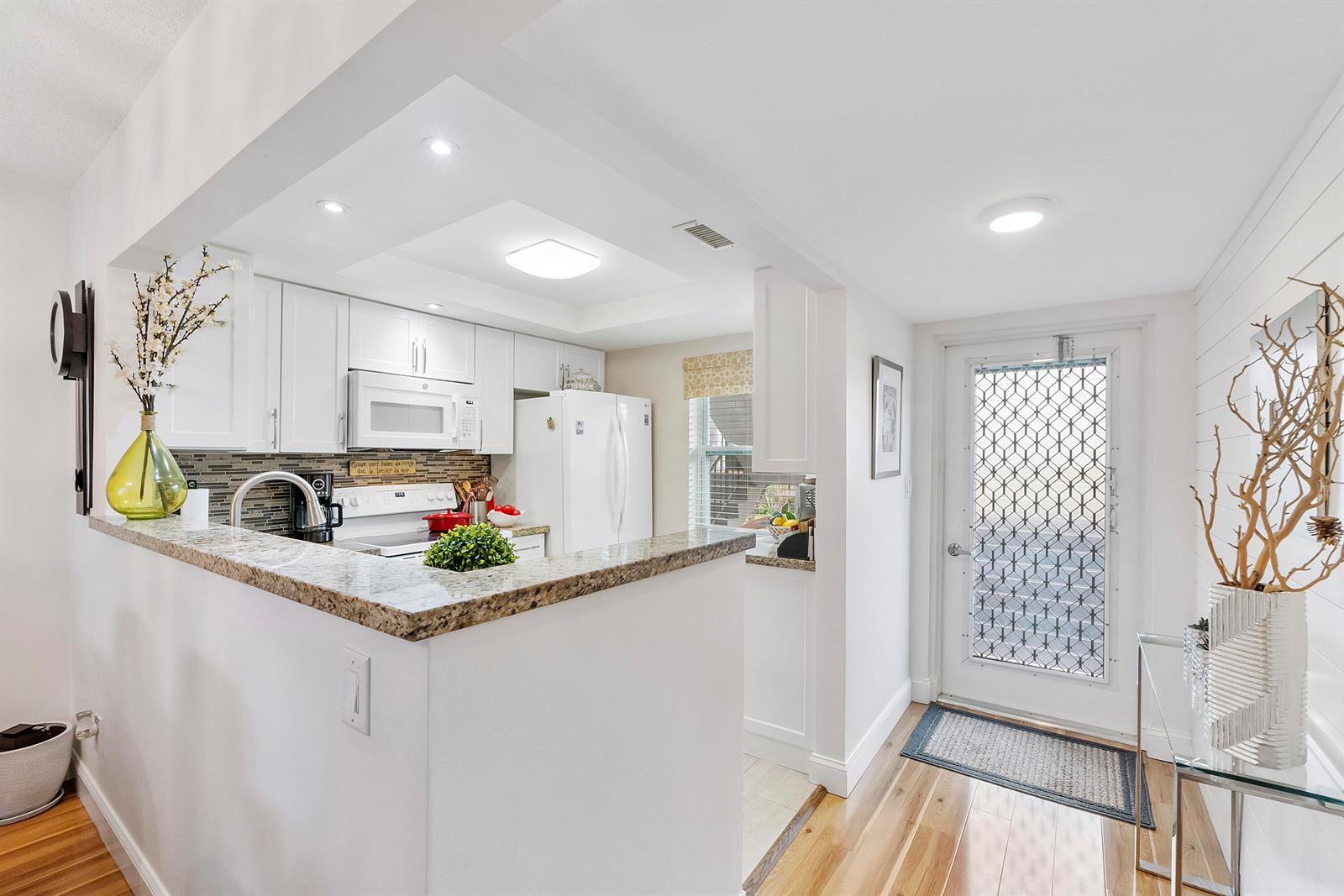 A kitchen with white cabinets, granite countertops, and a glass-paned door leading outside — 7837 Golf Circle Drive # 212, Margate FL 33063, MARGATE, FL