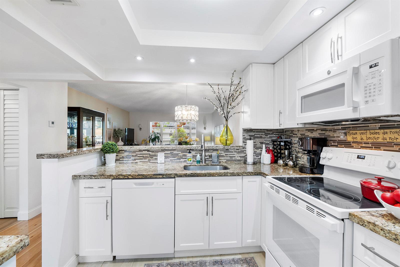 A kitchen features white cabinets, granite countertops, stainless steel appliances, and a tiled backsplash — 7837 Golf Circle Drive # 212, Margate FL 33063, MARGATE, FL
