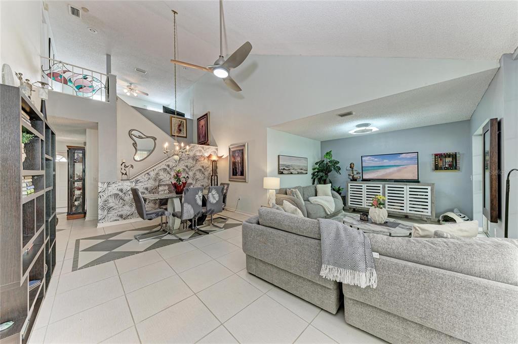A living and dining area with vaulted ceilings, tiled floors, and a staircase with wallpaper — 5209 34TH STREET COURT W UNIT 261, BRADENTON, FL