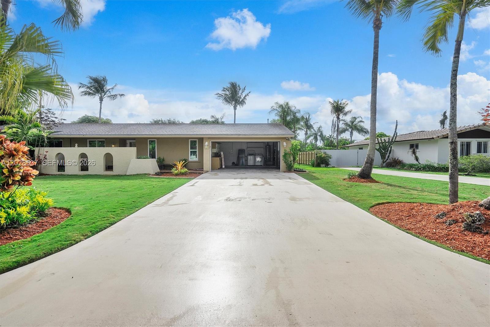 A single-story house with a concrete driveway and an open garage under a blue sky — 13241 SW 99th Ct, Miami FL 33176, MIAMI, FL