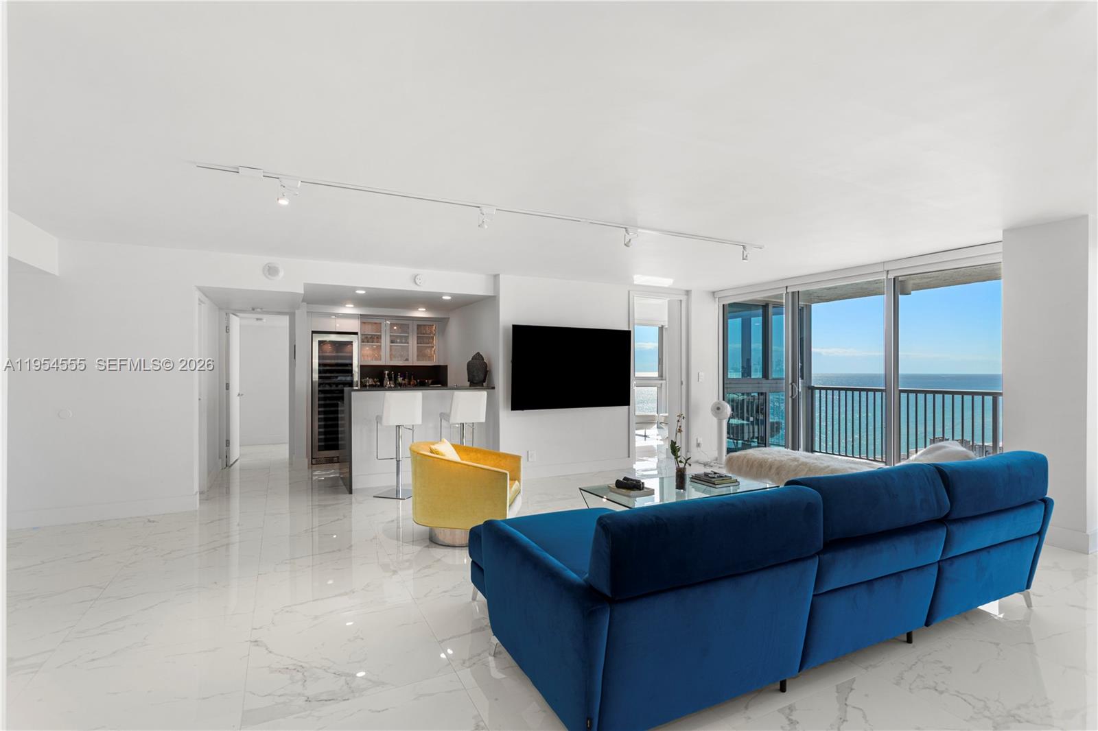 A bright living room features a blue sofa, yellow chair, bar area, and ocean views — 2655 Collins Ave, Miami Beach FL 33140, MIAMI BEACH, FL