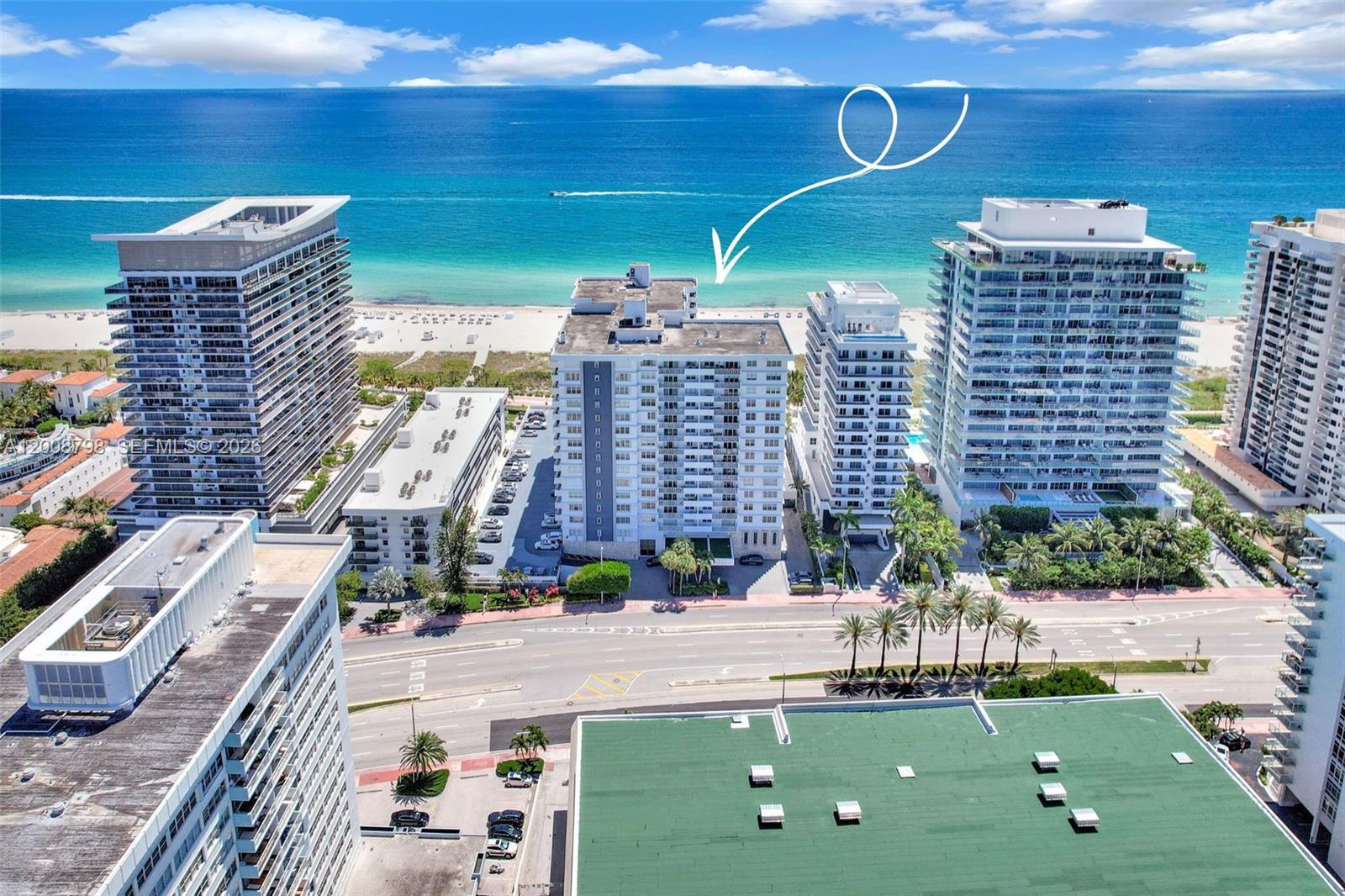 An aerial view shows several high-rise apartment buildings situated along a sandy beach and ocean — 5825 Collins Ave # 2E, Miami Beach FL 33140, MIAMI BEACH, FL