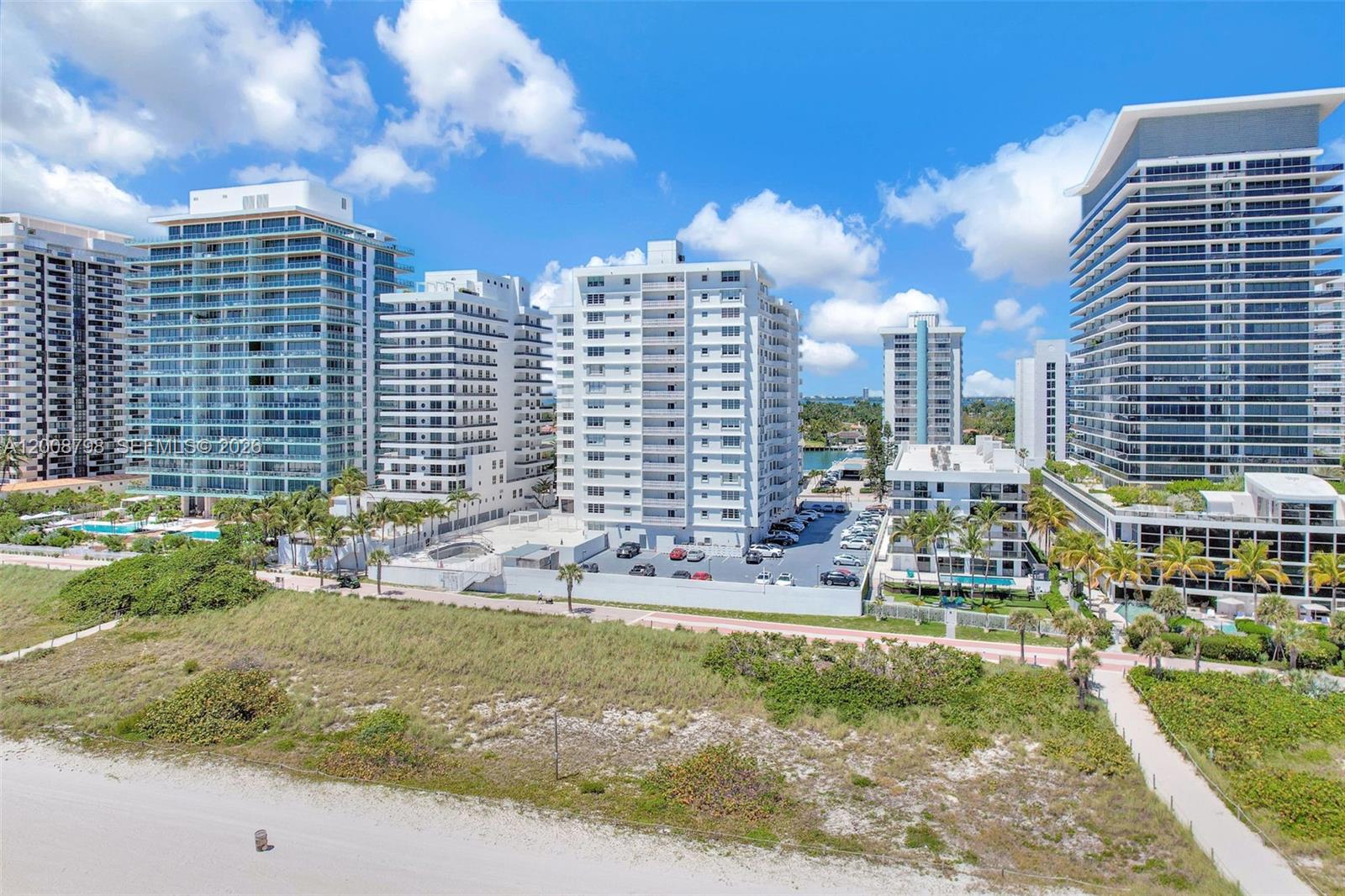 An aerial view shows several high-rise residential buildings situated along a sandy beach — 5825 Collins Ave # 2E, Miami Beach FL 33140, MIAMI BEACH, FL