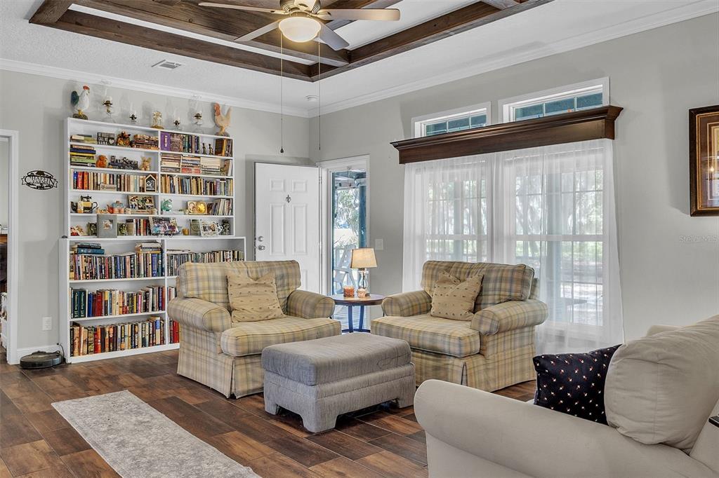 A living room features a white bookshelf, two plaid armchairs, and a coffered wood ceiling — 601 PURVIS ROAD, SEVILLE, FL