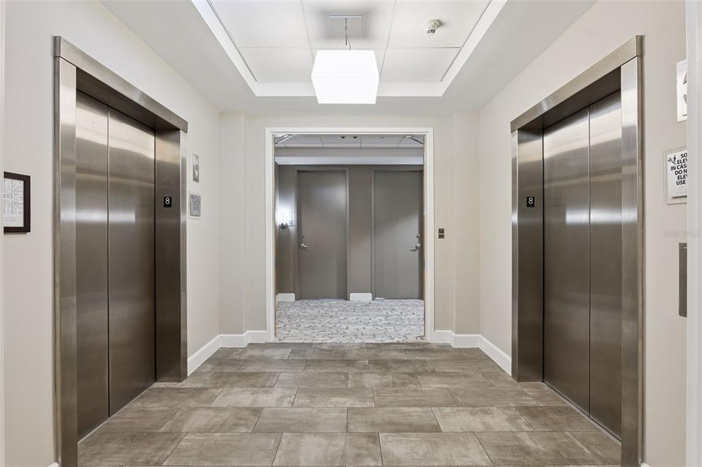 A hallway features two stainless steel elevators, tile flooring, and a doorway leading to rooms — 101 S EOLA DRIVE UNIT 815, ORLANDO, FL