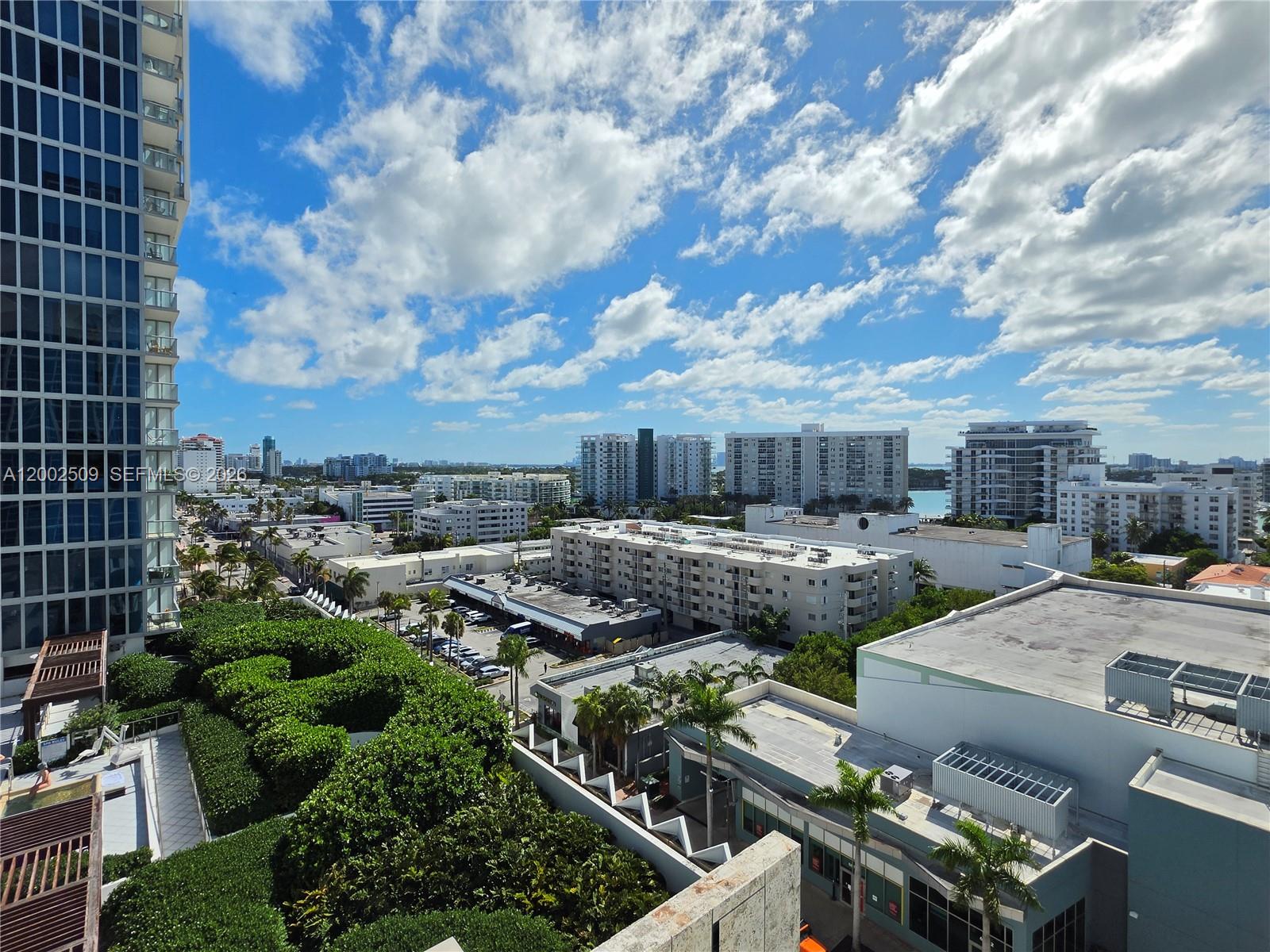 An elevated view shows a city skyline with apartment buildings, palm trees, and a parking lot — 6801 Collins Ave, Miami Beach FL 33141, MIAMI BEACH, FL
