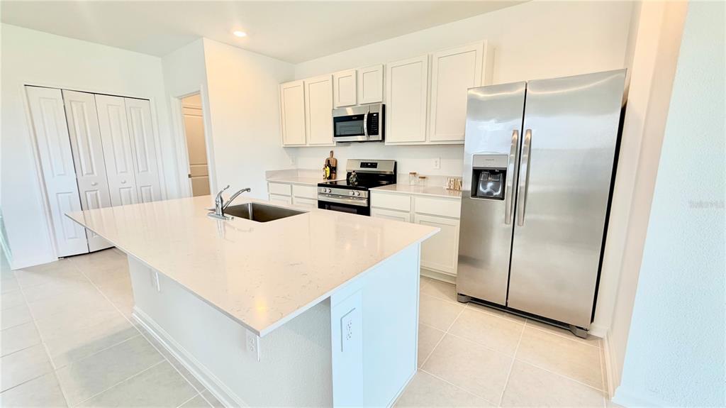 A modern kitchen features white cabinets, stainless steel appliances, and a large central island — 4034 OLD MILL ROAD, HAINES CITY, FL