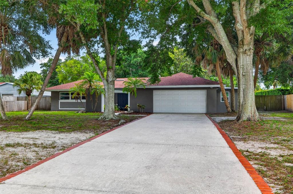 A single-story gray house with a white garage door and a concrete driveway — 1963 BELLEAIR ROAD, CLEARWATER, FL