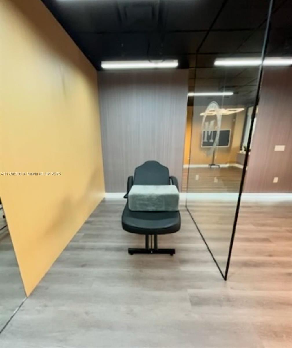 A room with light wood flooring, a yellow wall, and a black treatment chair — Confidential, West Miami FL 33144, WEST MIAMI, FL
