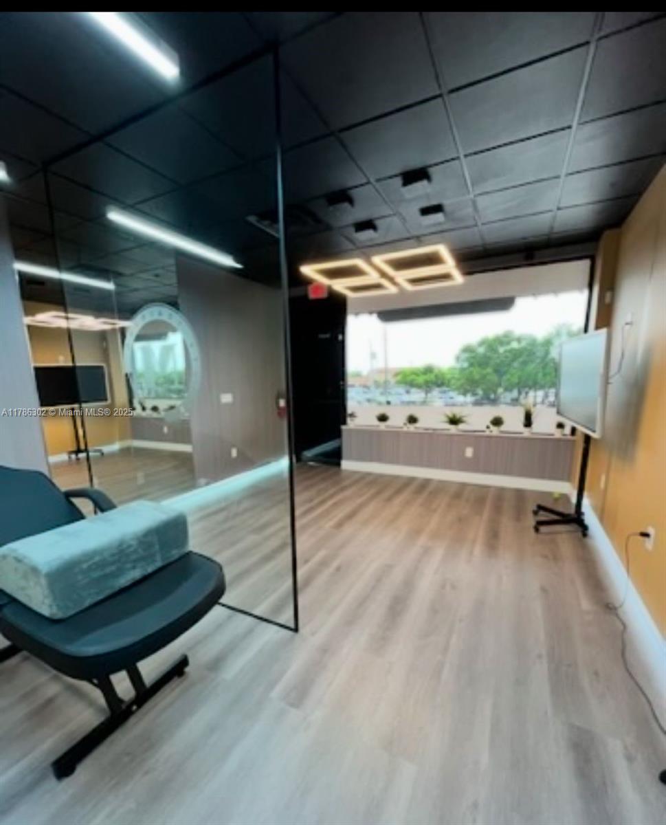 A modern room features light wood-look flooring, a large mirror, and a geometric ceiling light — Confidential, West Miami FL 33144, WEST MIAMI, FL