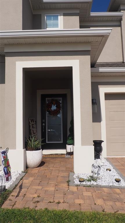 A tan house exterior features a paved walkway, a black front door, and white trim — 216 DENALI STREET, HAINES CITY, FL