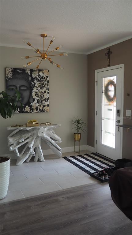An entryway features a white driftwood console table, a sputnik chandelier, and a black-and-white rug — 216 DENALI STREET, HAINES CITY, FL