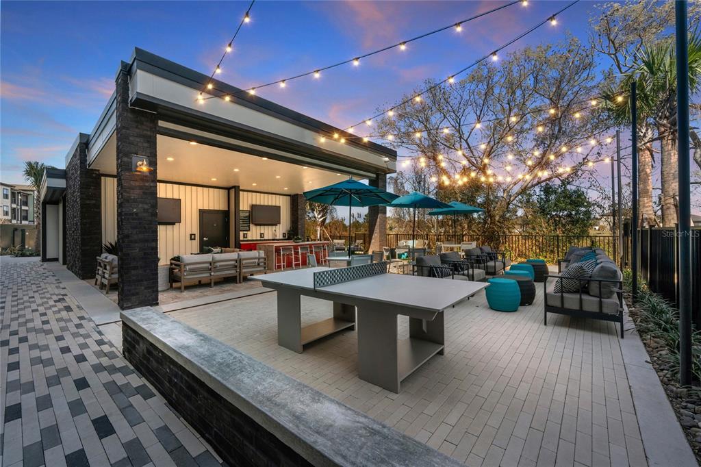An outdoor patio area features a ping pong table, lounge seating, and string lights — 2285 CROWN VILLAGE ROAD UNIT A1.S, OCOEE, FL