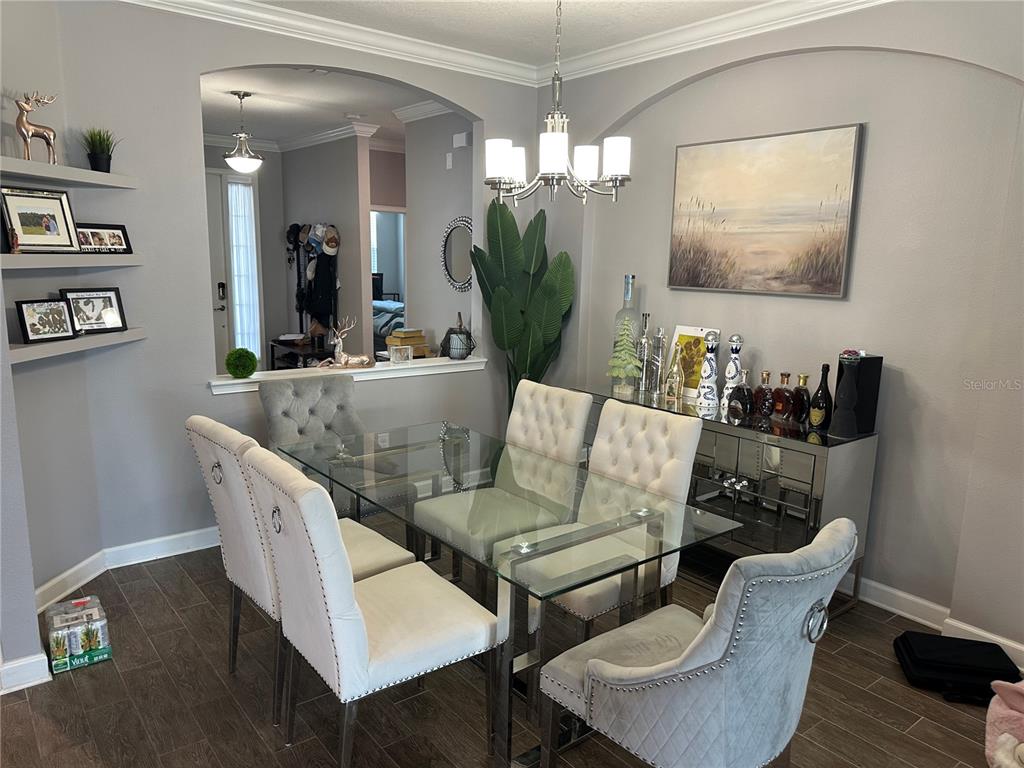 A dining room features a glass table, tufted chairs, a mirrored sideboard, and arched wall cutouts — 1424 CLUBMAN DRIVE, DAVENPORT, FL
