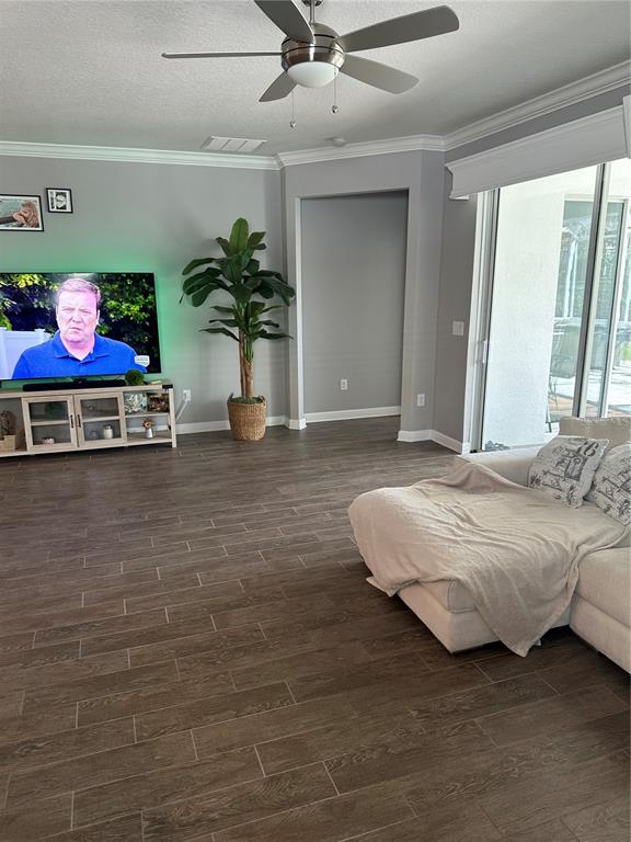 A living room features wood-look tile flooring, a ceiling fan, and a large television console — 1424 CLUBMAN DRIVE, DAVENPORT, FL
