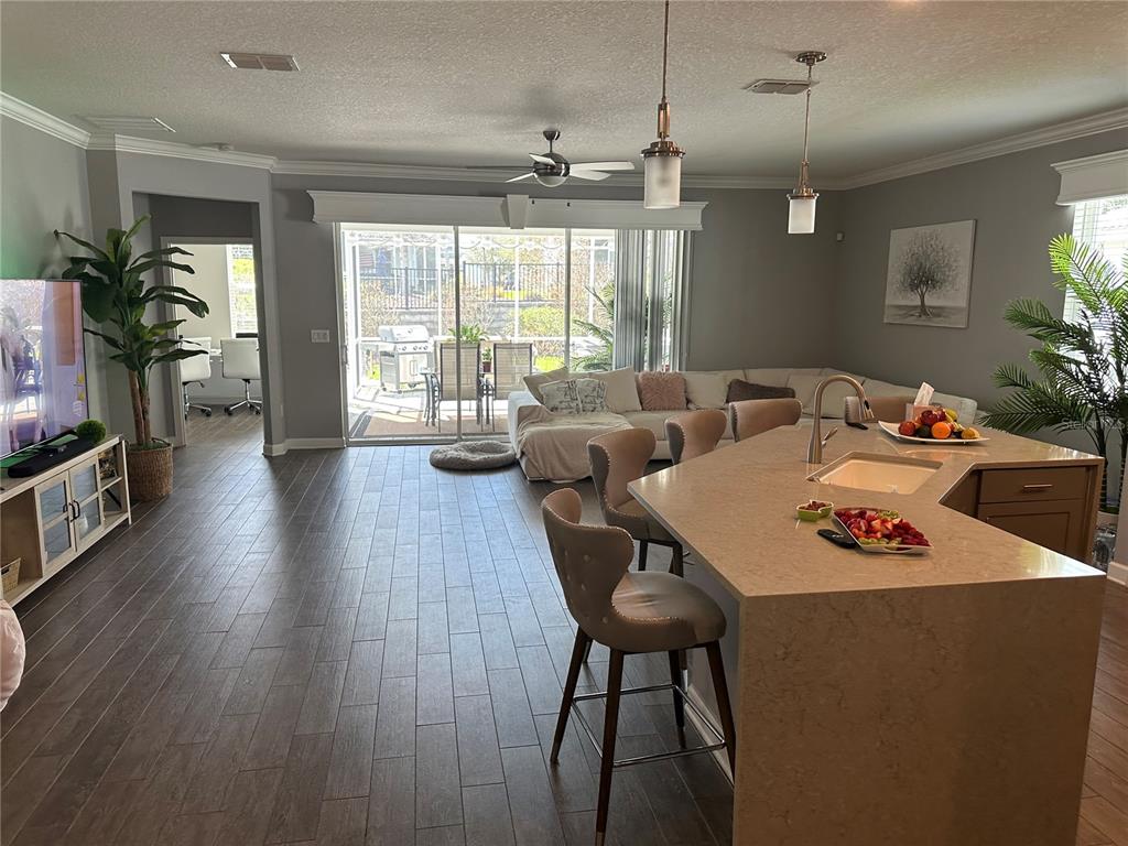 An open-concept kitchen and living area features a large island, tile floors, and sliding doors — 1424 CLUBMAN DRIVE, DAVENPORT, FL